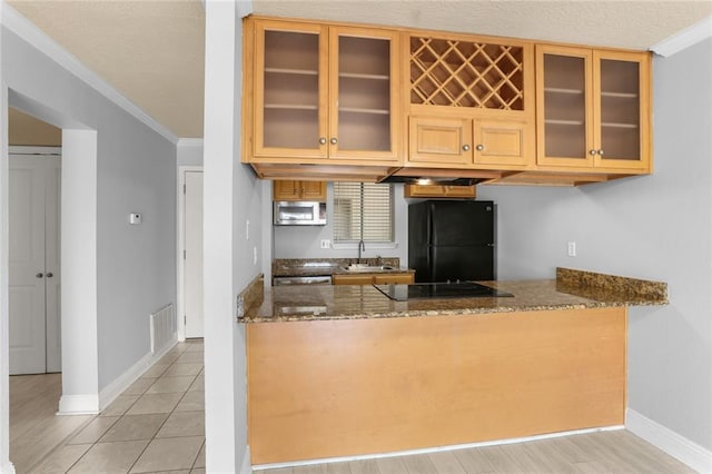 kitchen featuring sink, dark stone countertops, light tile patterned floors, black appliances, and ornamental molding