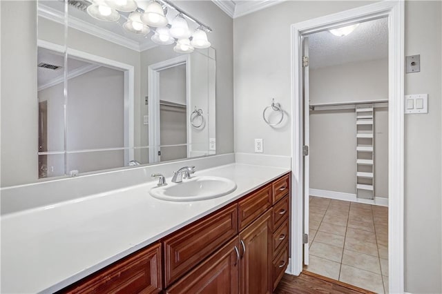 bathroom featuring tile patterned flooring, vanity, a textured ceiling, and ornamental molding