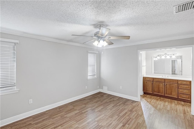 unfurnished bedroom featuring ceiling fan, sink, ornamental molding, and ensuite bathroom