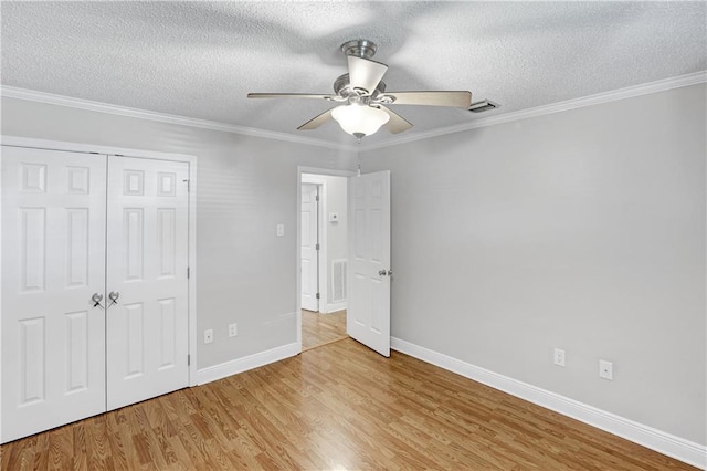 unfurnished bedroom with ceiling fan, crown molding, light hardwood / wood-style floors, a textured ceiling, and a closet