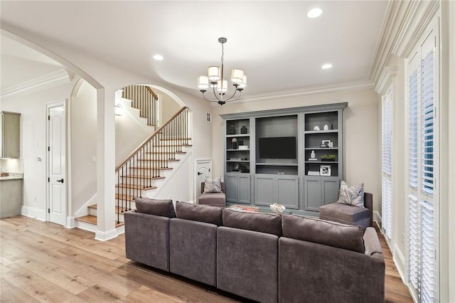 living room with a notable chandelier, light wood-type flooring, and ornamental molding