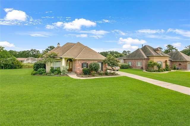 view of front of home with a chimney, a front lawn, and brick siding