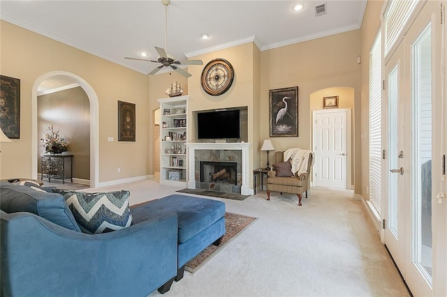 living area featuring ornamental molding, light colored carpet, visible vents, and arched walkways