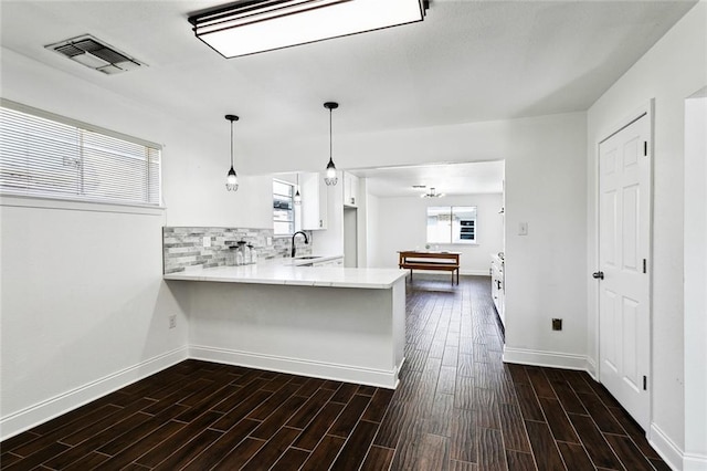 kitchen featuring backsplash, white cabinets, sink, hanging light fixtures, and kitchen peninsula