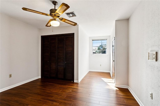 unfurnished bedroom with ceiling fan, dark hardwood / wood-style flooring, and a closet