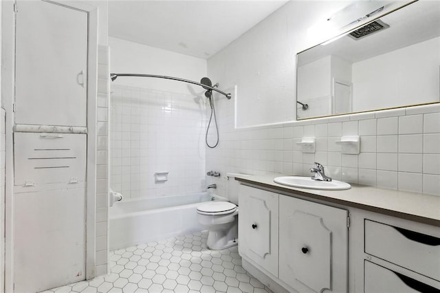 full bathroom featuring tile patterned floors, toilet, vanity, tile walls, and tiled shower / bath