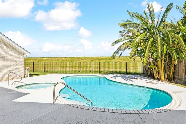 view of pool featuring an in ground hot tub, a patio, and a rural view