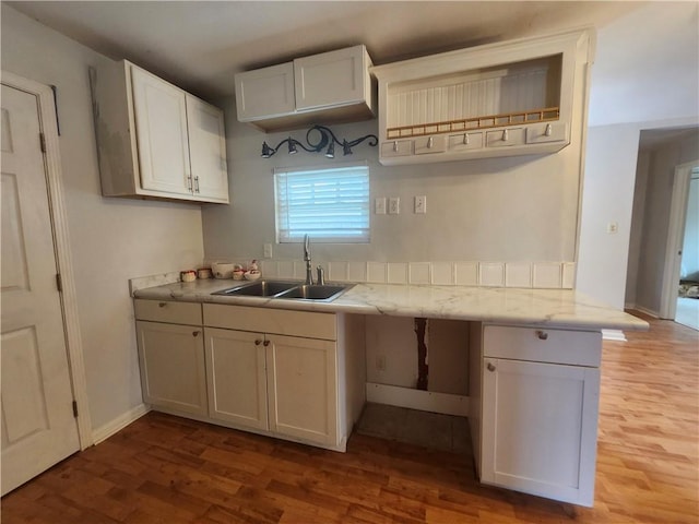 kitchen with light wood-type flooring, white cabinetry, and sink