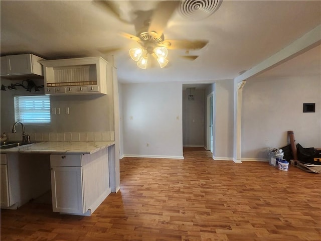 kitchen with light stone counters, ceiling fan, sink, light hardwood / wood-style floors, and white cabinetry