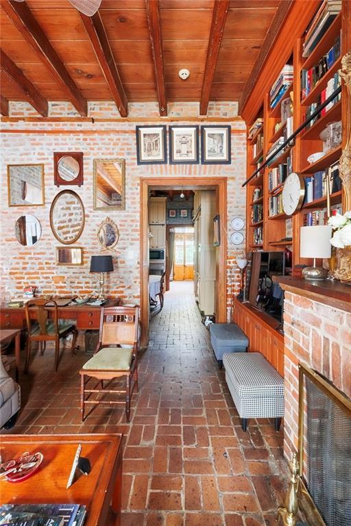 interior space with wood ceiling, beamed ceiling, and a brick fireplace