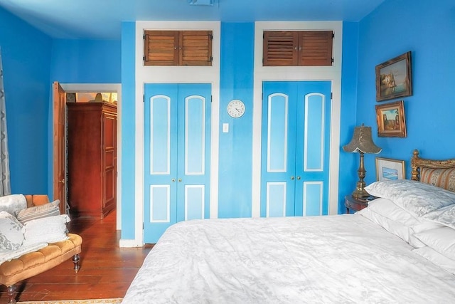 bedroom featuring dark hardwood / wood-style flooring and two closets