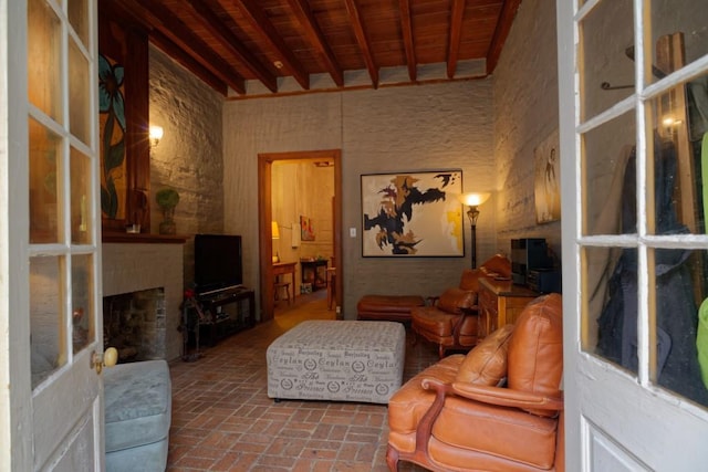 living room featuring a brick fireplace, wooden ceiling, and lofted ceiling with beams