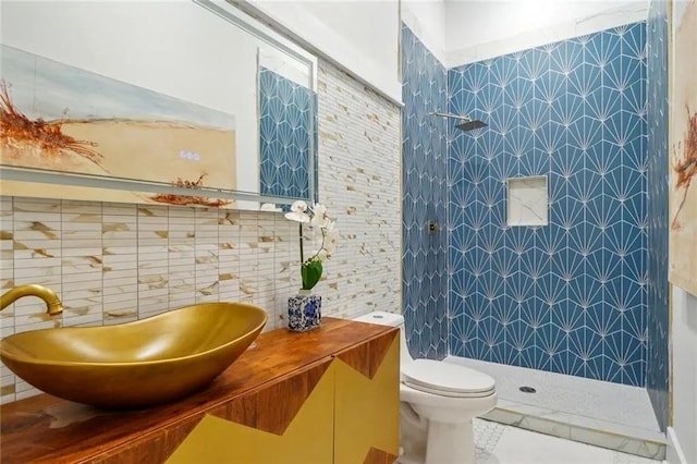 bathroom featuring sink, tile patterned flooring, toilet, tile walls, and a tile shower