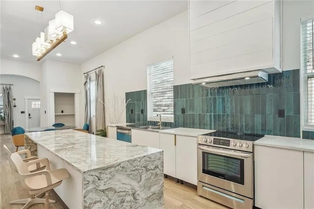 kitchen with appliances with stainless steel finishes, a kitchen island, sink, white cabinetry, and hanging light fixtures