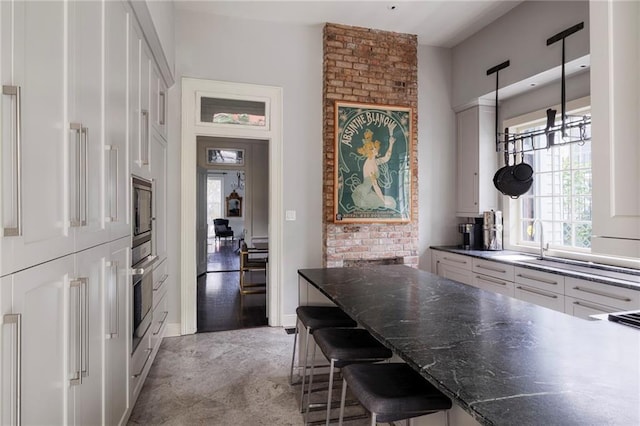 kitchen with pendant lighting, a breakfast bar, white cabinets, sink, and stainless steel appliances