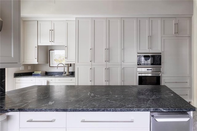 kitchen with white cabinets, stainless steel oven, black microwave, and dark stone counters