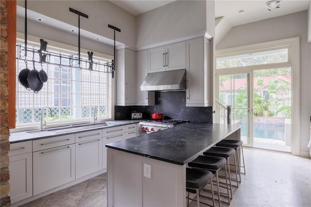 kitchen featuring a kitchen breakfast bar, tasteful backsplash, pendant lighting, white cabinets, and plenty of natural light