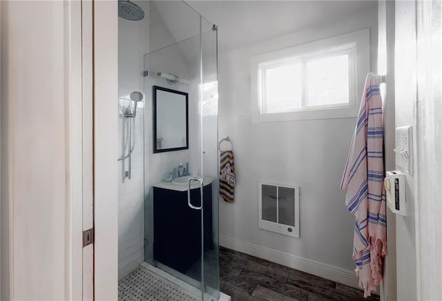 bathroom featuring a tile shower, heating unit, and sink