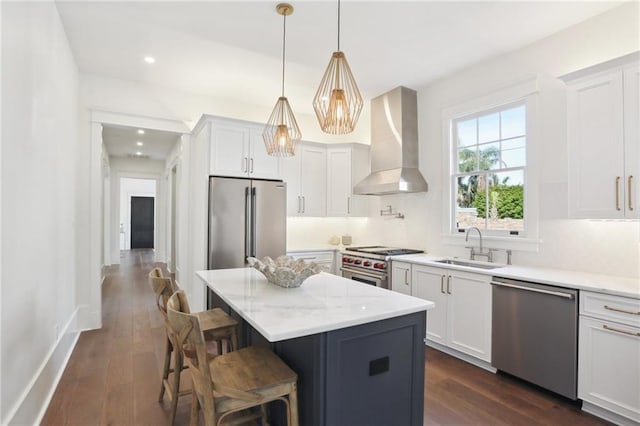 kitchen featuring high quality appliances, white cabinets, wall chimney exhaust hood, decorative backsplash, and a kitchen island