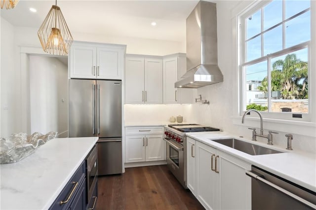 kitchen with white cabinets, pendant lighting, high end appliances, and wall chimney range hood