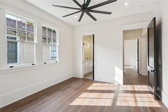 unfurnished bedroom with ensuite bath, ceiling fan, and wood-type flooring