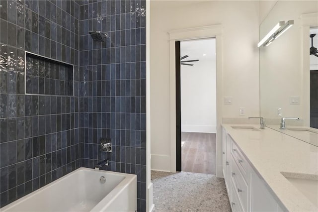 bathroom featuring ceiling fan, vanity, and tiled shower / bath combo