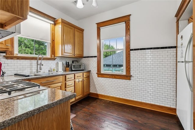 kitchen with white refrigerator, sink, dark wood-type flooring, and a wealth of natural light