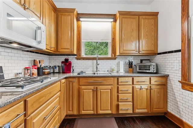 kitchen featuring sink, dark wood-type flooring, stainless steel gas cooktop, tasteful backsplash, and stone countertops