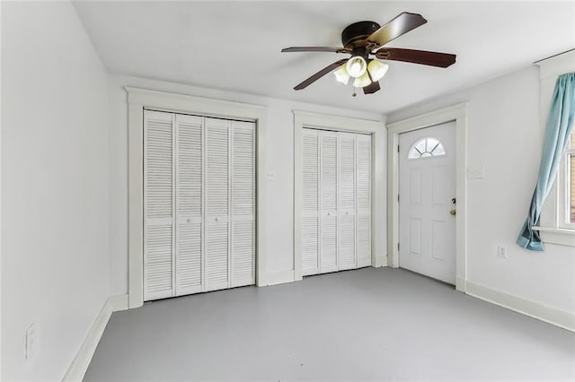 interior space with multiple closets, ceiling fan, and concrete floors