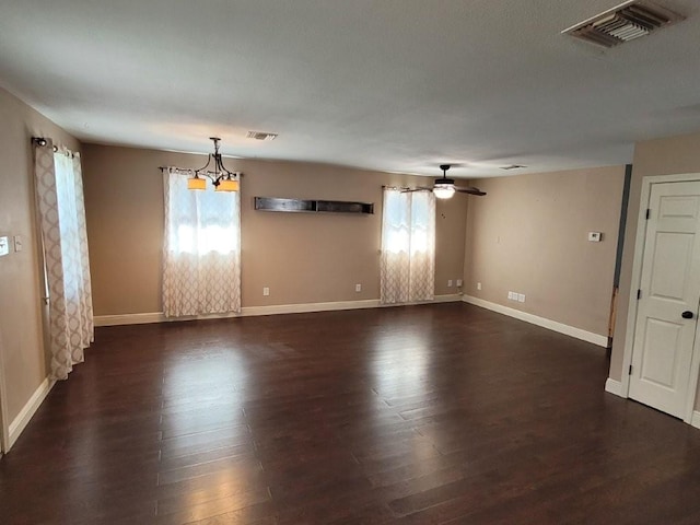 unfurnished room with ceiling fan with notable chandelier and dark hardwood / wood-style floors