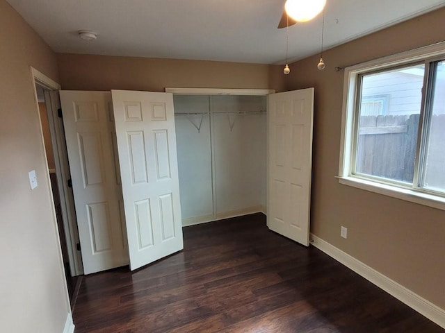 unfurnished bedroom featuring dark hardwood / wood-style floors, ceiling fan, and a closet