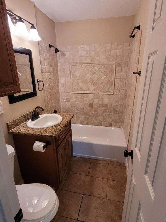 full bathroom featuring tiled shower / bath, tile patterned flooring, vanity, and toilet