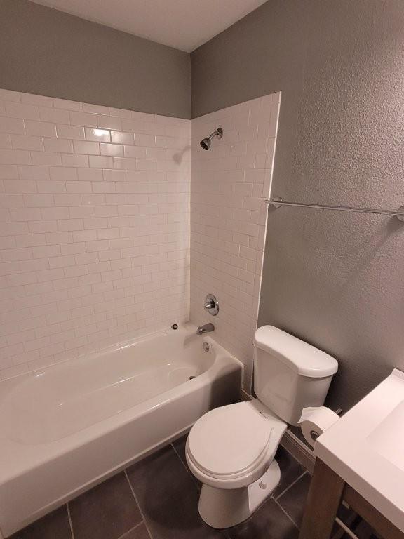 bathroom featuring toilet, tile patterned flooring, and tiled shower / bath