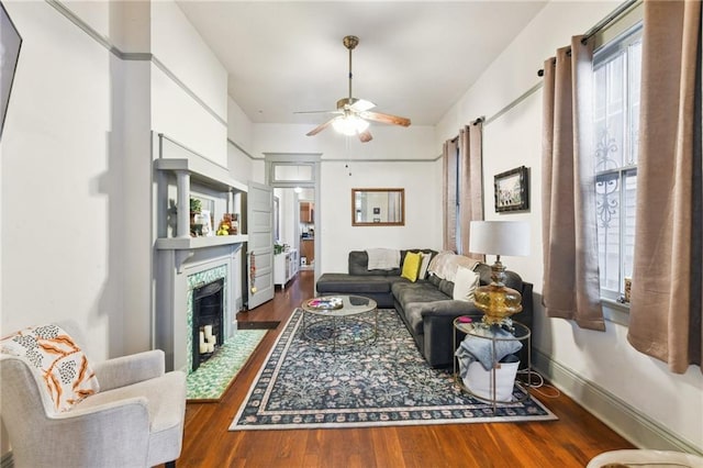 living room featuring dark hardwood / wood-style flooring, a tile fireplace, and ceiling fan