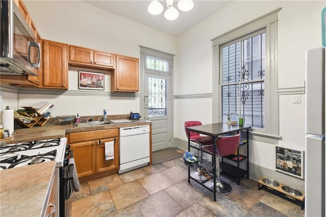 kitchen featuring sink, gas range, an inviting chandelier, fridge, and dishwasher