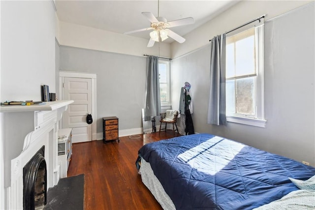 bedroom with multiple windows, dark hardwood / wood-style flooring, and ceiling fan