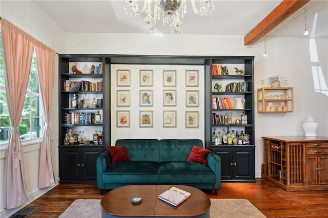 living area featuring dark wood-type flooring, a chandelier, and beam ceiling