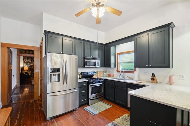 kitchen with stainless steel appliances, light stone countertops, sink, and dark hardwood / wood-style floors