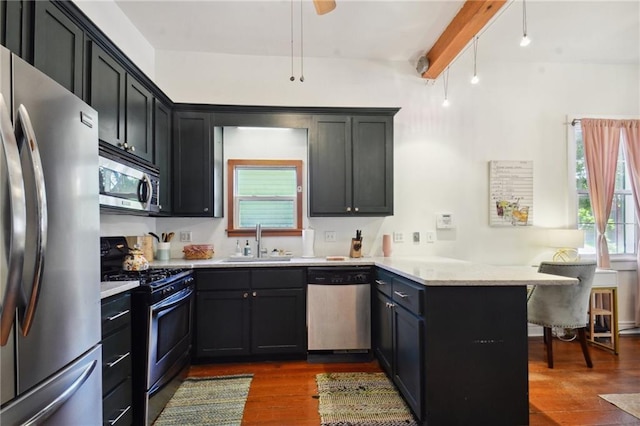 kitchen featuring appliances with stainless steel finishes, sink, dark hardwood / wood-style flooring, kitchen peninsula, and beam ceiling