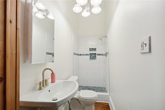 bathroom featuring sink, hardwood / wood-style flooring, toilet, and tiled shower