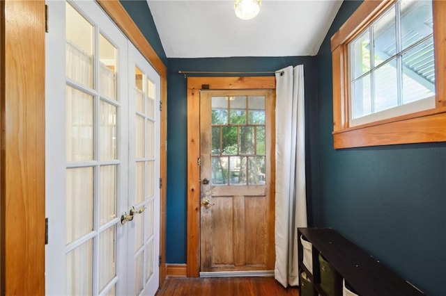 doorway to outside with dark wood-type flooring, plenty of natural light, and vaulted ceiling