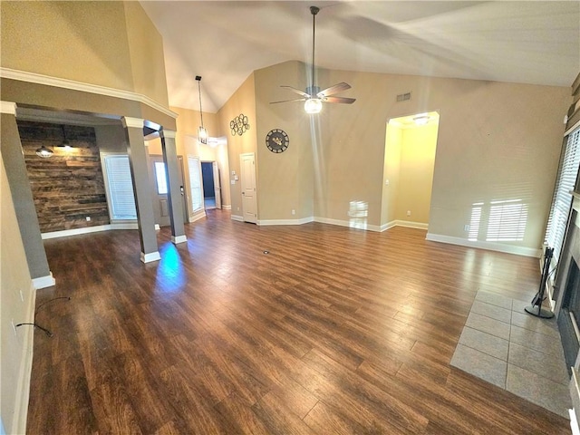 unfurnished living room with ceiling fan, a tiled fireplace, dark wood-type flooring, and lofted ceiling