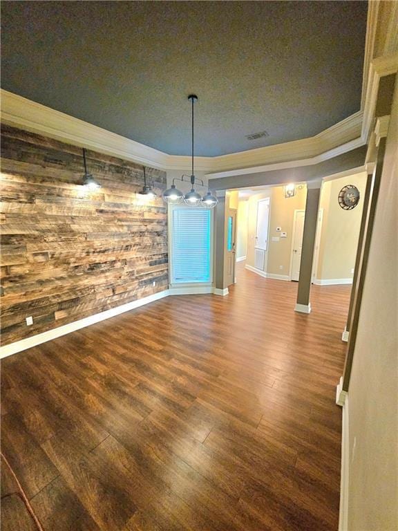 unfurnished dining area featuring a textured ceiling, dark wood-type flooring, wooden walls, and ornamental molding