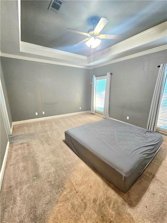 bedroom with ceiling fan, carpet, crown molding, and a tray ceiling