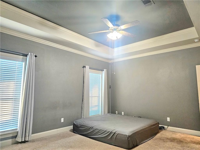 carpeted bedroom with ceiling fan, ornamental molding, and a raised ceiling