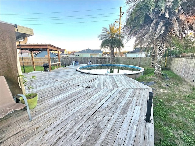 wooden deck with a fenced in pool and a yard