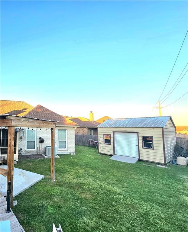 view of yard featuring a garage, cooling unit, and an outbuilding