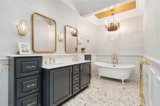 bathroom with a bathing tub, vanity, a notable chandelier, and ornamental molding