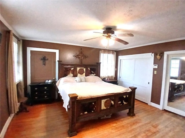 bedroom featuring hardwood / wood-style floors, ceiling fan, ornamental molding, and multiple windows