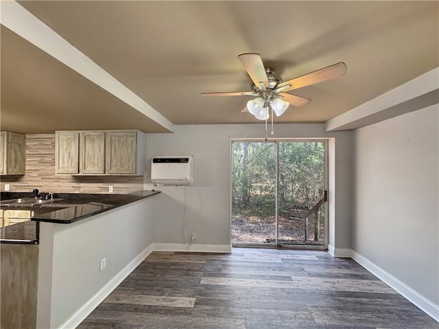 kitchen with a wall mounted air conditioner, decorative backsplash, kitchen peninsula, sink, and dark stone countertops